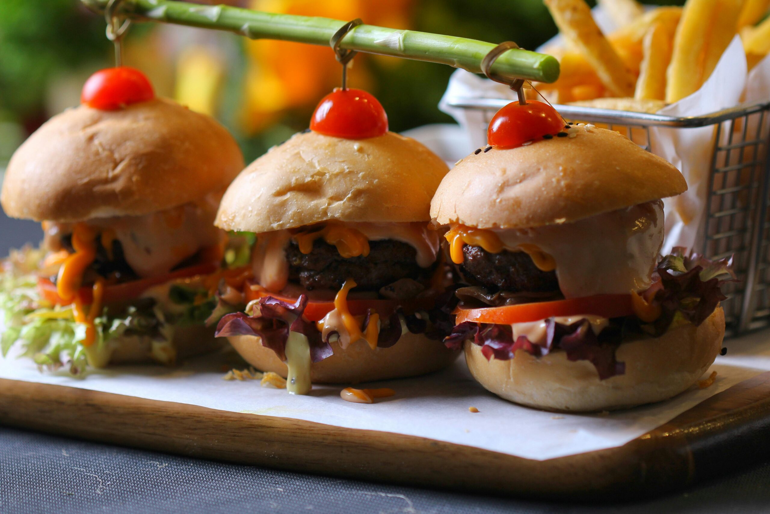 Delicious gourmet mini burgers with fries, topped with cherry tomatoes, perfect for a mouth-watering lunch.