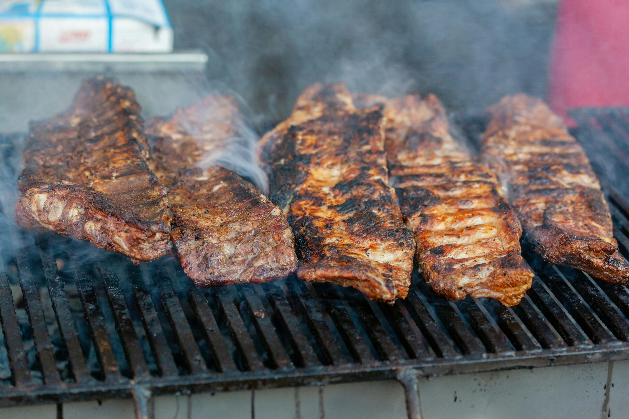 Close-up of delicious grilled ribs smoking on a barbecue grill, perfect for a summer cookout.